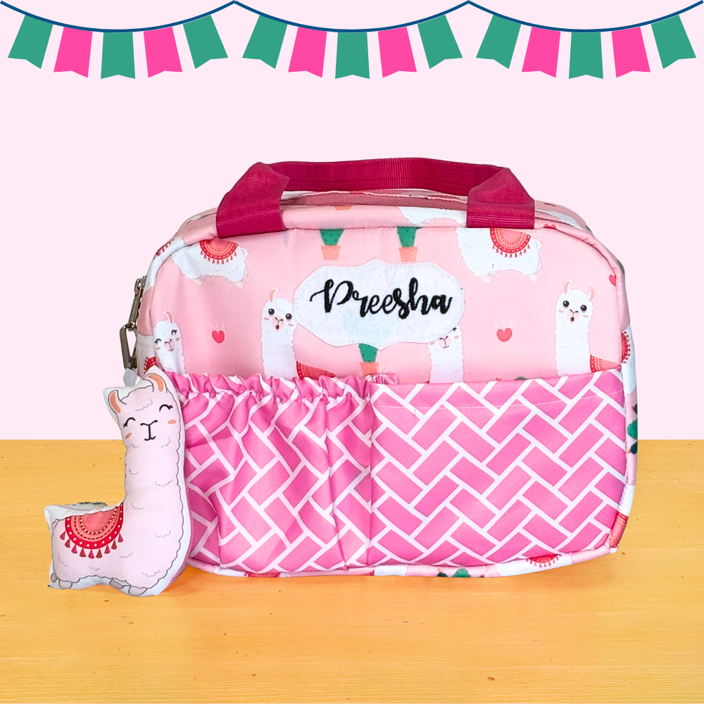 Pink diaper bag with llama pattern and small llama plush toy