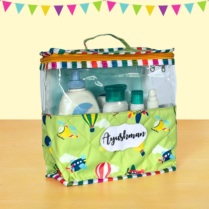 Clear travel bag with colorful striped top and green base featuring cartoon design